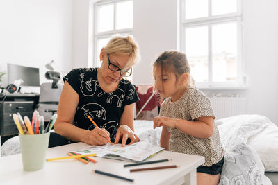 Grandmother teaching granddaughter at home