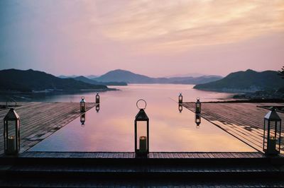 Lanterns on pier in lake during sunset