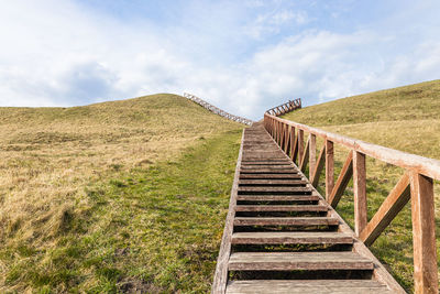 Pier over field against sky