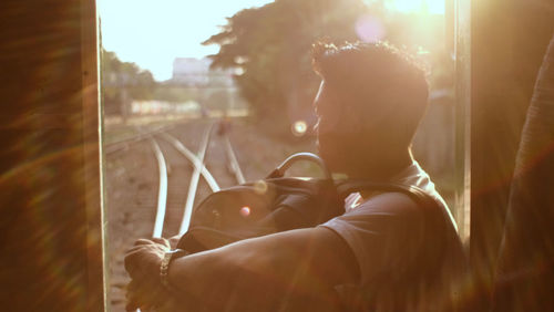 Side view of man looking through train window