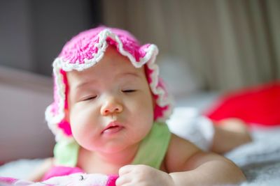 Cute baby girl with eyes closed lying on bed