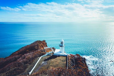 Lighthouse by sea against sky