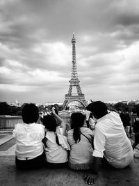 Rear view of people in city against cloudy sky