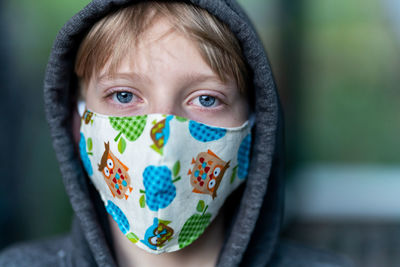 Close up of young person wearing face mask with hood on looking tired