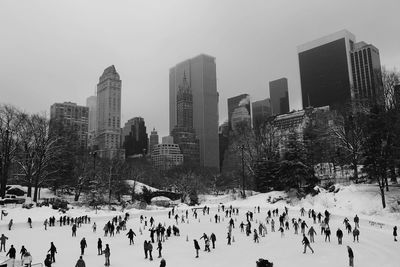 People ice-skating against towers in city
