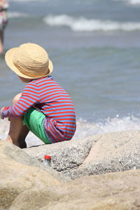 Boy wearing hat sitting at beach