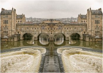 Arch bridge over river against buildings in city