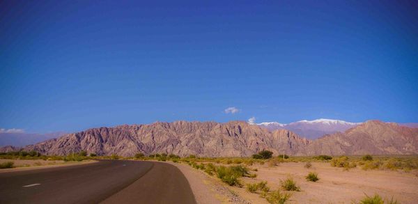 Road amidst desert against blue sky