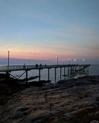 Pier over sea against sky during sunset