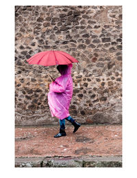 Full length of woman with umbrella standing in rain