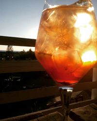 Close-up of wineglass against orange sky