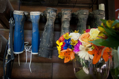Flowers in vase against shoe rack at shop