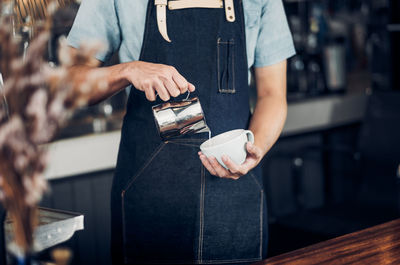 Midsection of barista making coffee in cafe