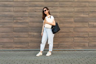 Young woman standing against brick wall