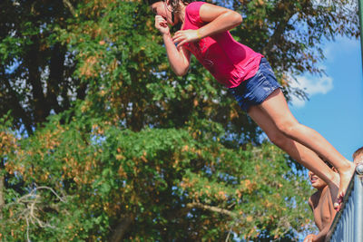 Low angle view of girl and plants against trees