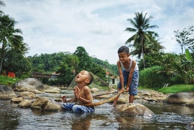 Rear view of friends with arms raised against trees