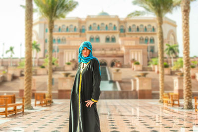 Young woman with umbrella against built structure