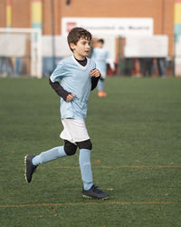 Portrait of young boy play on the grass football field in the stadium during a match in cold weather