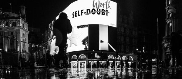 Reflection of man in swimming pool in city