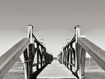 Wooden pier leading towards sea against clear sky