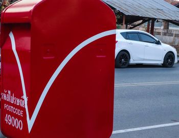 Side view of red car on road in city