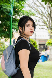 Latin college girl with blue hair walking through the park dressed in black and blue bag