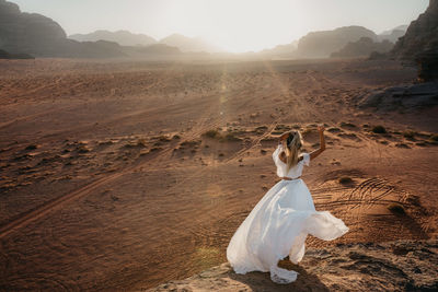 Woman in dress standing on landscape against sky