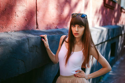 Portrait of young woman standing by building