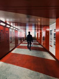 Rear view of man standing on illuminated corridor