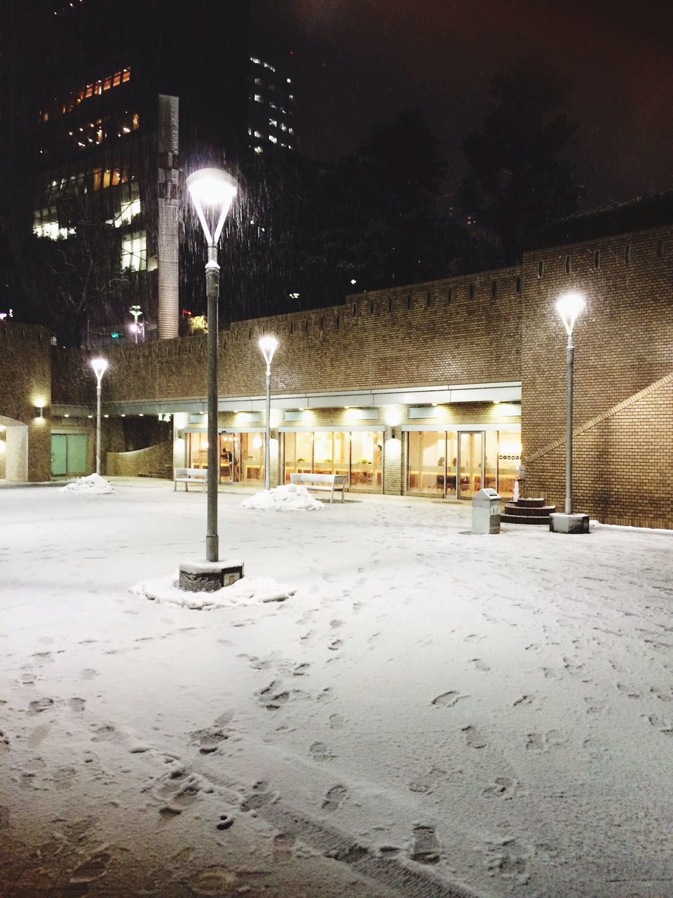 illuminated, night, street light, built structure, architecture, lighting equipment, building exterior, empty, street, the way forward, absence, transportation, city, light - natural phenomenon, building, outdoors, no people, snow, road, incidental people