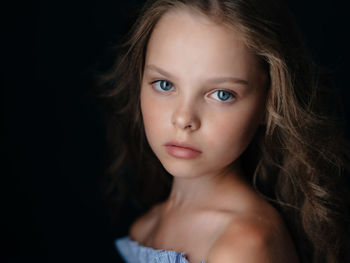 Close-up portrait of young woman against black background