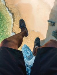 Low section of man standing over beach