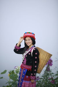 Woman wearing hat standing against wall