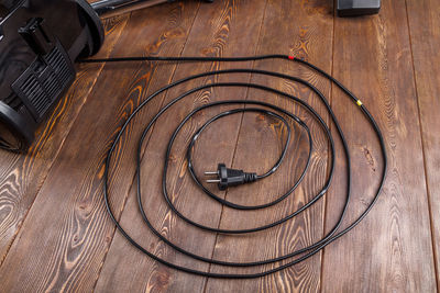 Power wire of black vacuum cleaner on wooden surface