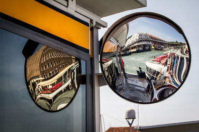 Reflection of ferry in grand canal on road mirror against sky