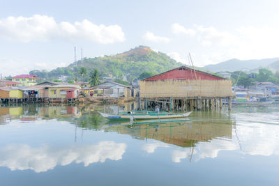 Houses by lake and mountains against sky