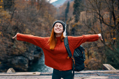 Happy young woman standing against tree