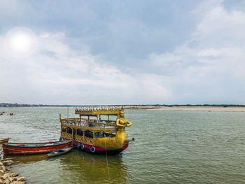 Fishing boat moored in sea against sky