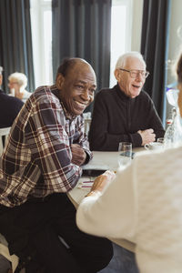 Smiling senior man talking with friend in nursing home