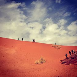 People walking on desert against sky