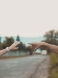 Hands of person with arms raised against sky