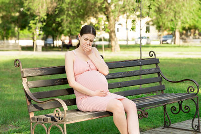 Young woman sitting on bench in park