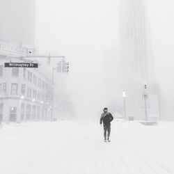 Man walking on snowcapped road in city during winter