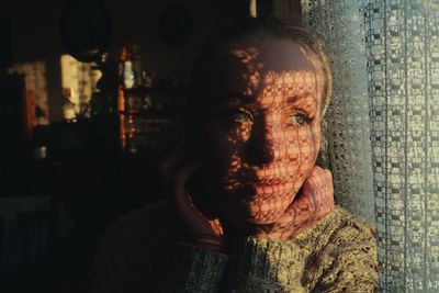 Close-up of young woman looking away by window with shadow