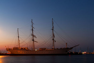 Sailboats in sea against clear sky during sunset