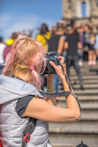 Woman photographing people while standing on staircase in city