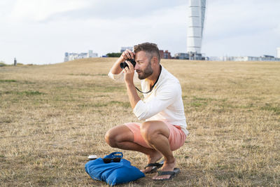 Mid-adult man crouching with camera