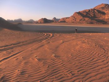 Scenic view of sand dunes at beach against sky