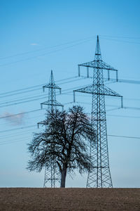 Low angle view of electricity pylon on field against sky