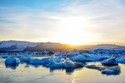 Scenic view of frozen lake against sky during sunset